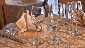 Une table à manger dressée avec des verres à vin, des assiettes et des couverts, donnant sur la rue.
