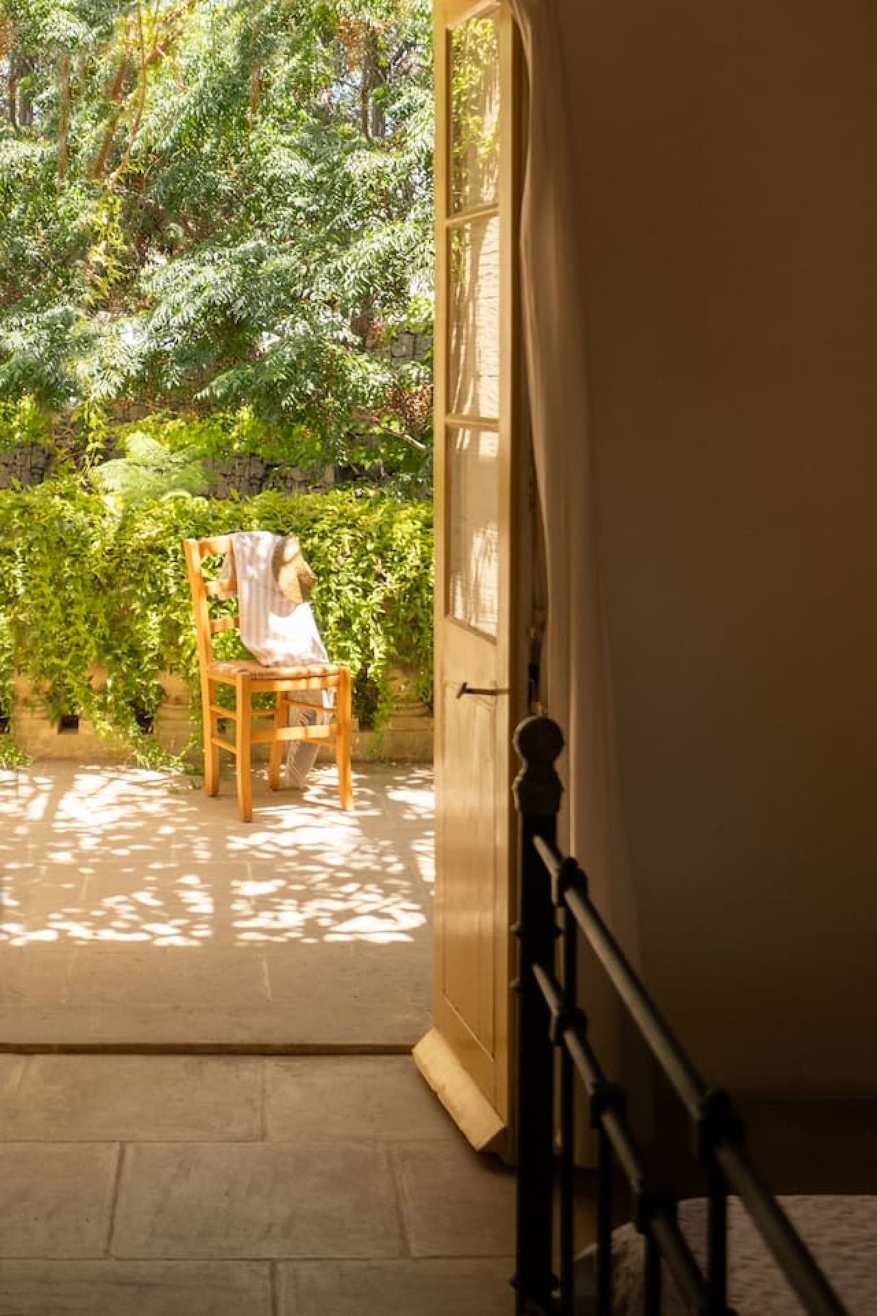 Une pièce avec une chaise en bois et une table devant une porte, donnant sur un jardin.