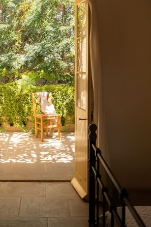 Ein Zimmer mit Holzstuhl und Tisch vor einer Tür, mit Blick auf einen Garten.