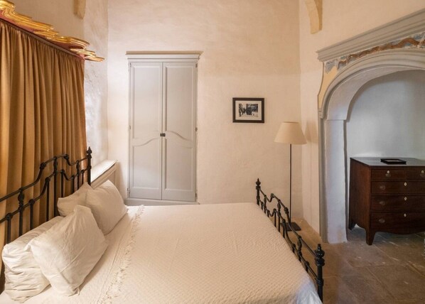 A bedroom with a bed, a wardrobe, a dresser, and a fireplace.