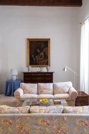 A living room with a sofa, a coffee table, a painting on the wall, a lamp, and a floor lamp.