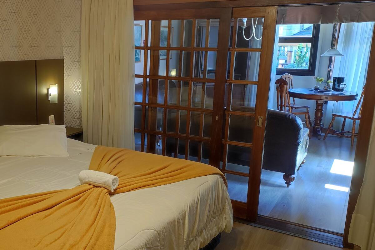 Una habitación de hotel con una cama, una mesita de noche, una ventana con cortinas y vistas al exterior.