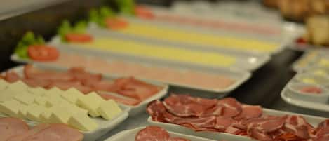 A buffet with various food items including sliced meats and cheeses.