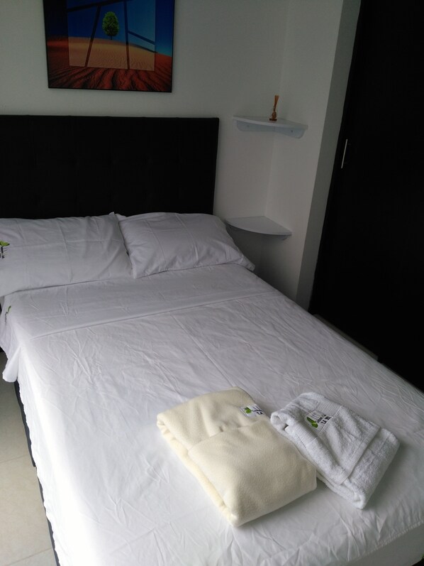 A hotel room with two beds, a nightstand, a wall-mounted shelf, and a painting.