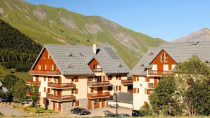 Una hilera de edificios de estilo chalet con balcones, con montañas al fondo.