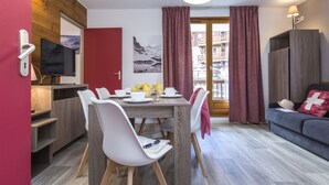 Una sala de estar moderna con comedor, televisor y un sofá con cojín.