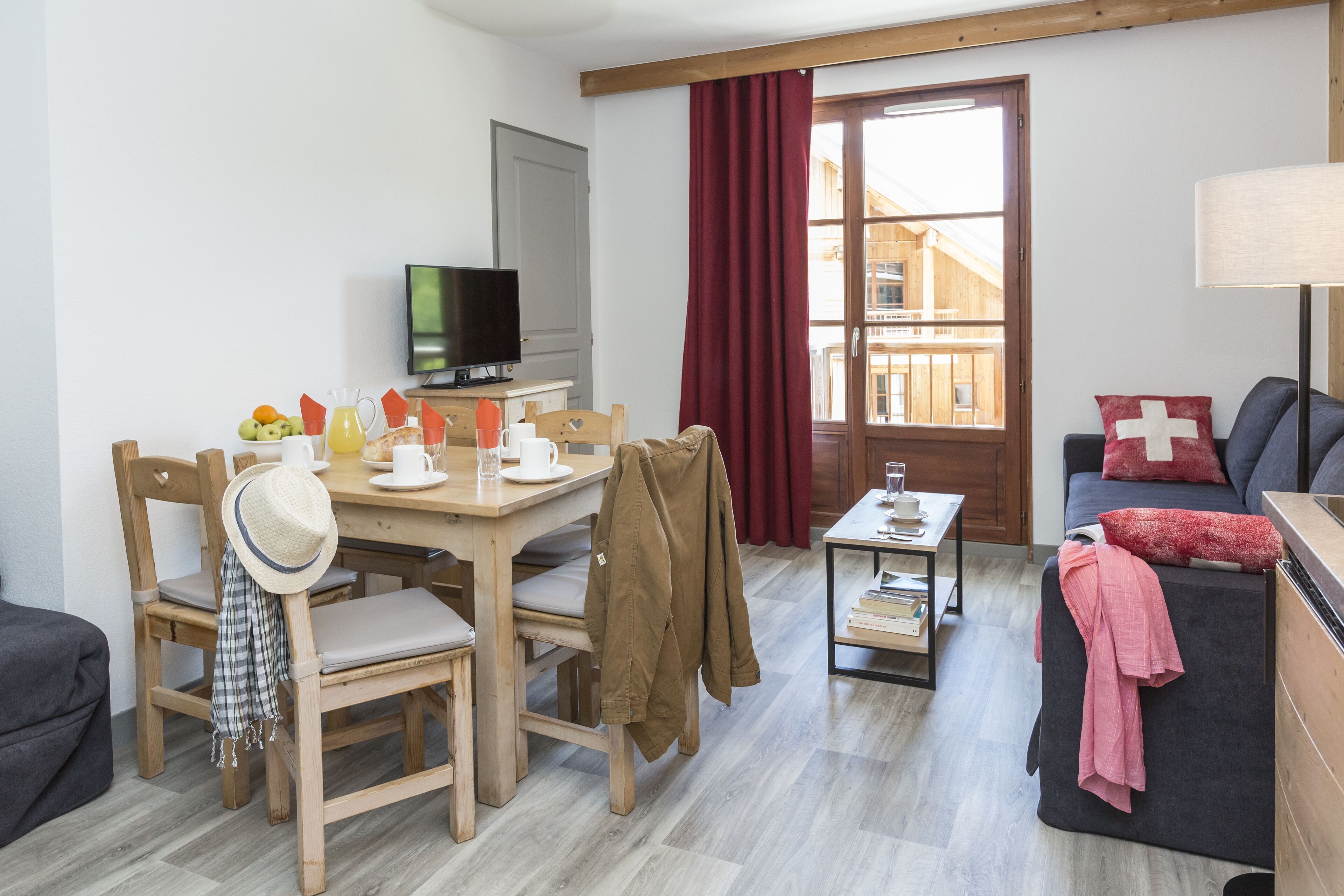 Una sala de estar acogedora con comedor, televisor y ventana con cortinas.