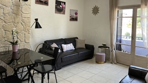 Una sala de estar acogedora con un sofá de cuero negro, una mesa de comedor de vidrio y una pared de piedra.