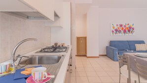 A modern kitchen with a sink, stove, and dining area with chairs and a table. - Alexis House Varenna (Varenna)