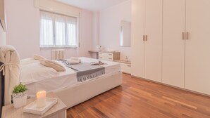 A modern bedroom with a large bed, bedside tables, a dresser, and a wardrobe. - Alexis House Varenna (Varenna)