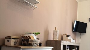 Een moderne keuken met witte kasten, een aanrecht met een koffieapparaat en een televisie aan de muur.