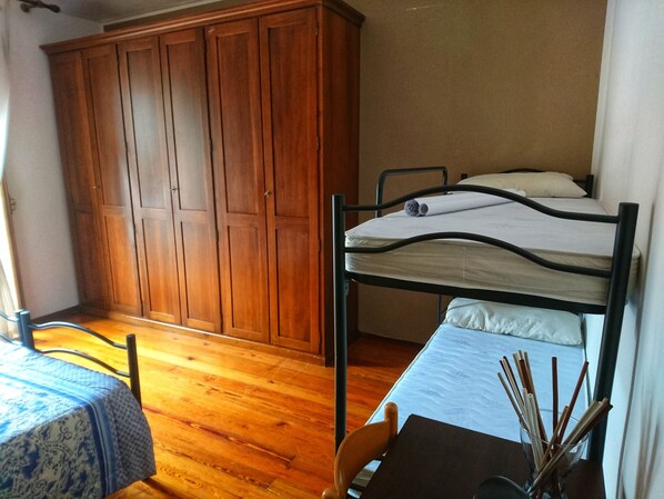 A bedroom with a bunk bed, wooden wardrobe, and a table with a patterned tablecloth. - GRAN TORINO - LOVELY FLAT (Torino)