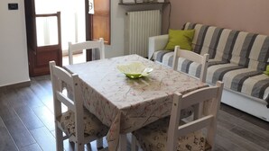 Een eethoek met een tafel, stoelen, een radiator, een klok en een bank.