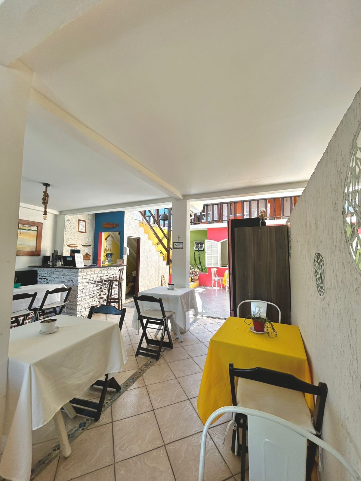 Een restaurant met terras, een trap naar een kleurrijk gebouw, en een wit interieur.