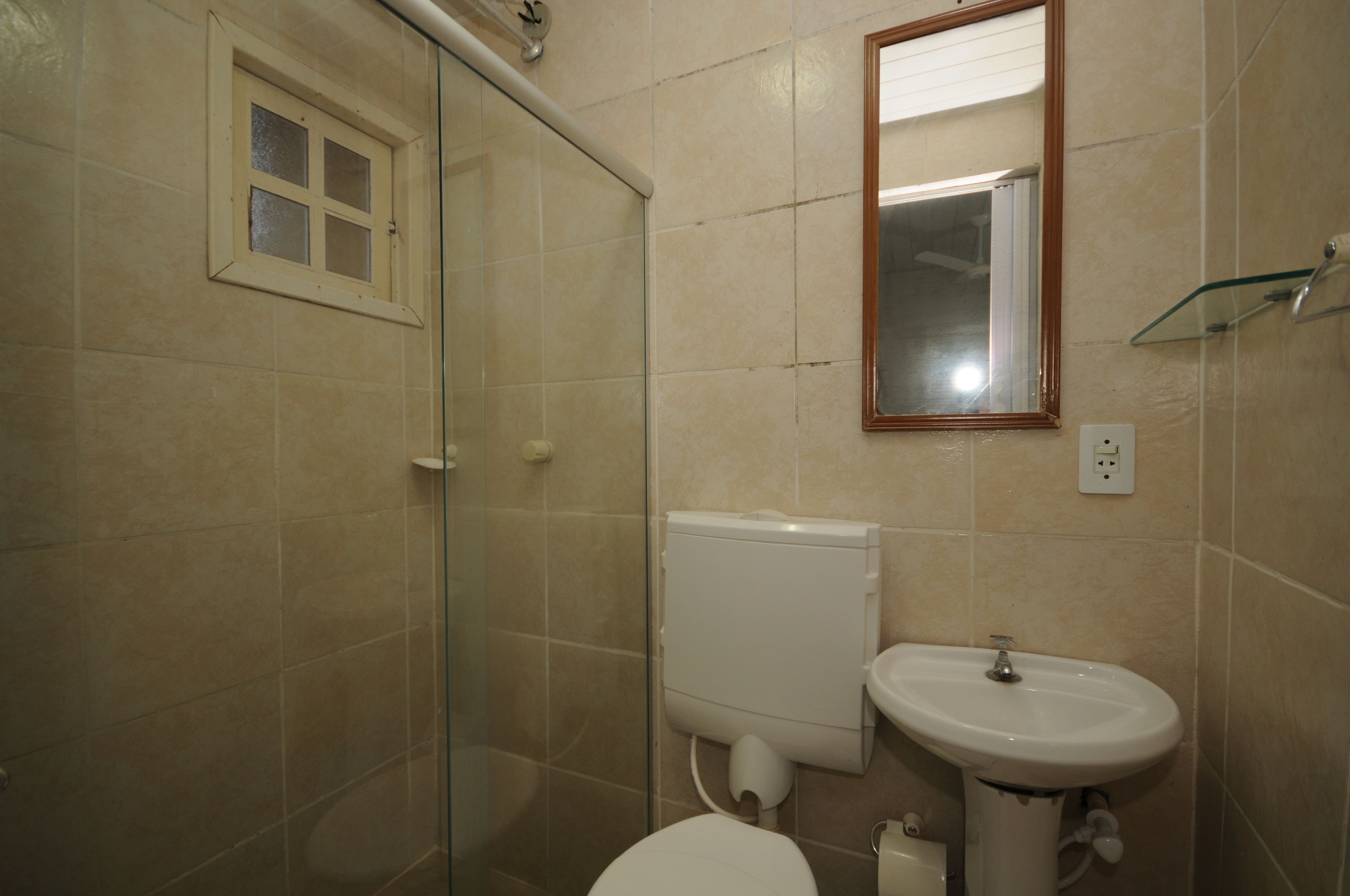 Un baño con cabina de ducha de vidrio, inodoro y lavamanos.