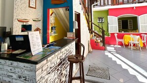 A reception area with a counter, a computer, and a seating area with a table and chairs. - Pousada Aldeia Buzios (Búzios)