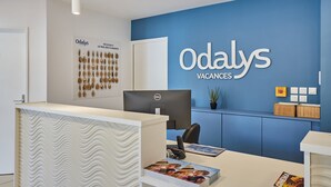 A reception desk with a Dell computer, a blue wall with 'Odaly's Vacances' signage, and a wall-mounted display of keys. - Résidence Odalys Le Mas des Flamants (Aigues-Mortes)