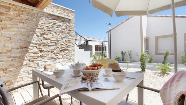 Un patio con una mesa dispuesta para el desayuno, incluyendo pan, huevos y bebidas.
