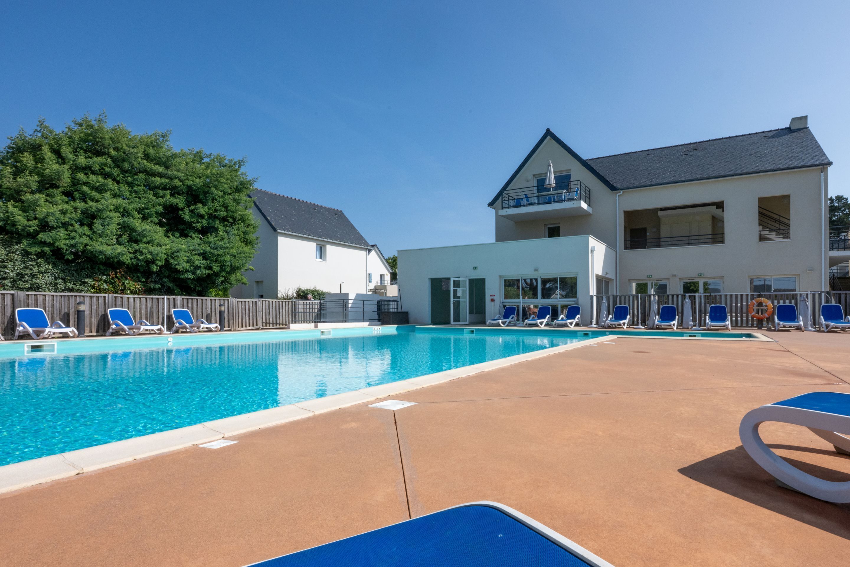 Ein Swimmingpool mit blauen Liegestühlen und ein Gebäude mit einem Balkon.