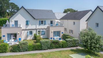 Ein zweistöckiges Haus mit Balkon, einer Terrasse und Gartenmöbeln sowie einem gepflegten Garten.
