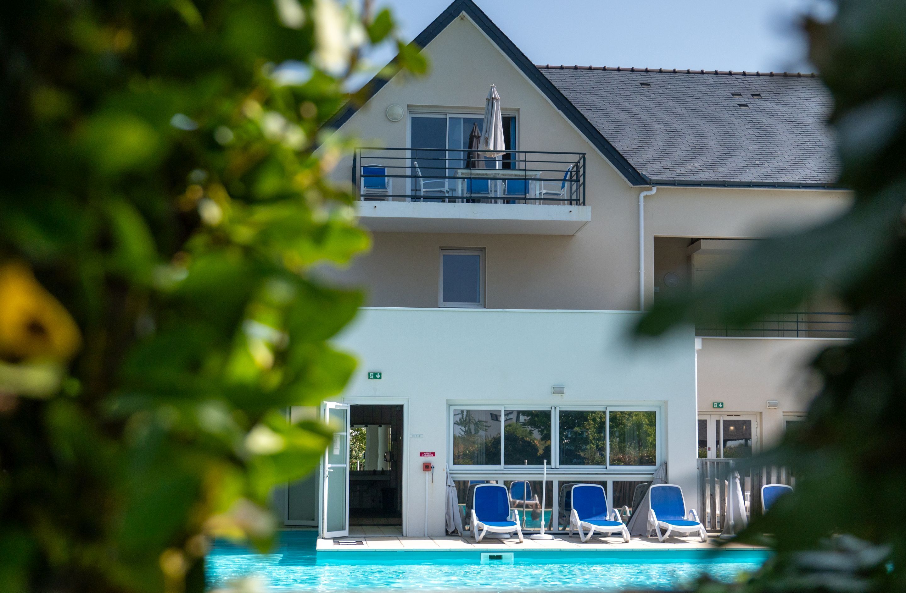 A hotel with a pool area, including lounge chairs and a covered seating area.