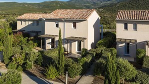 A modern two-story house with a tiled roof, surrounded by well-maintained gardens and a mountainous backdrop. - Résidence Odalys Les Villas de Bel Godère (Belgodere)