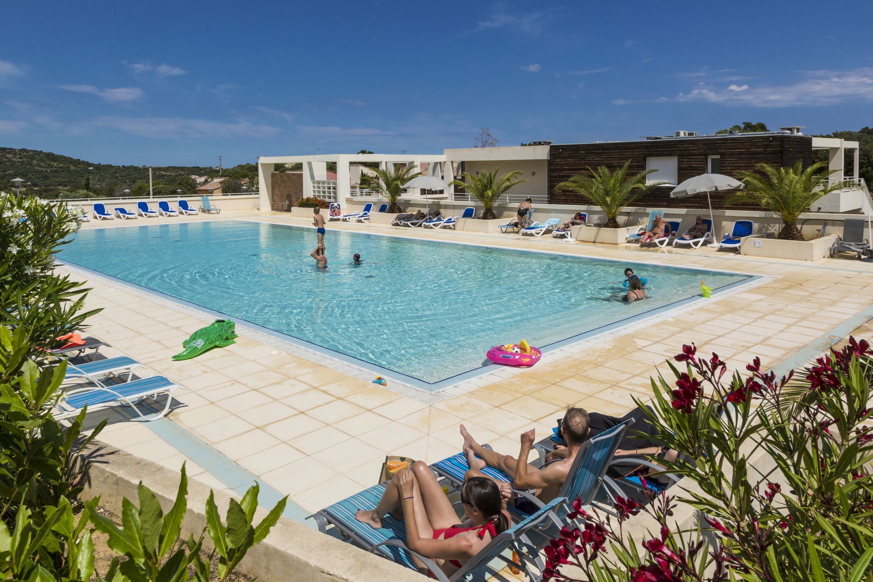 Ein Poolbereich mit Liegestühlen, einem Schwimmbecken und einem Gebäude im modernen Design.