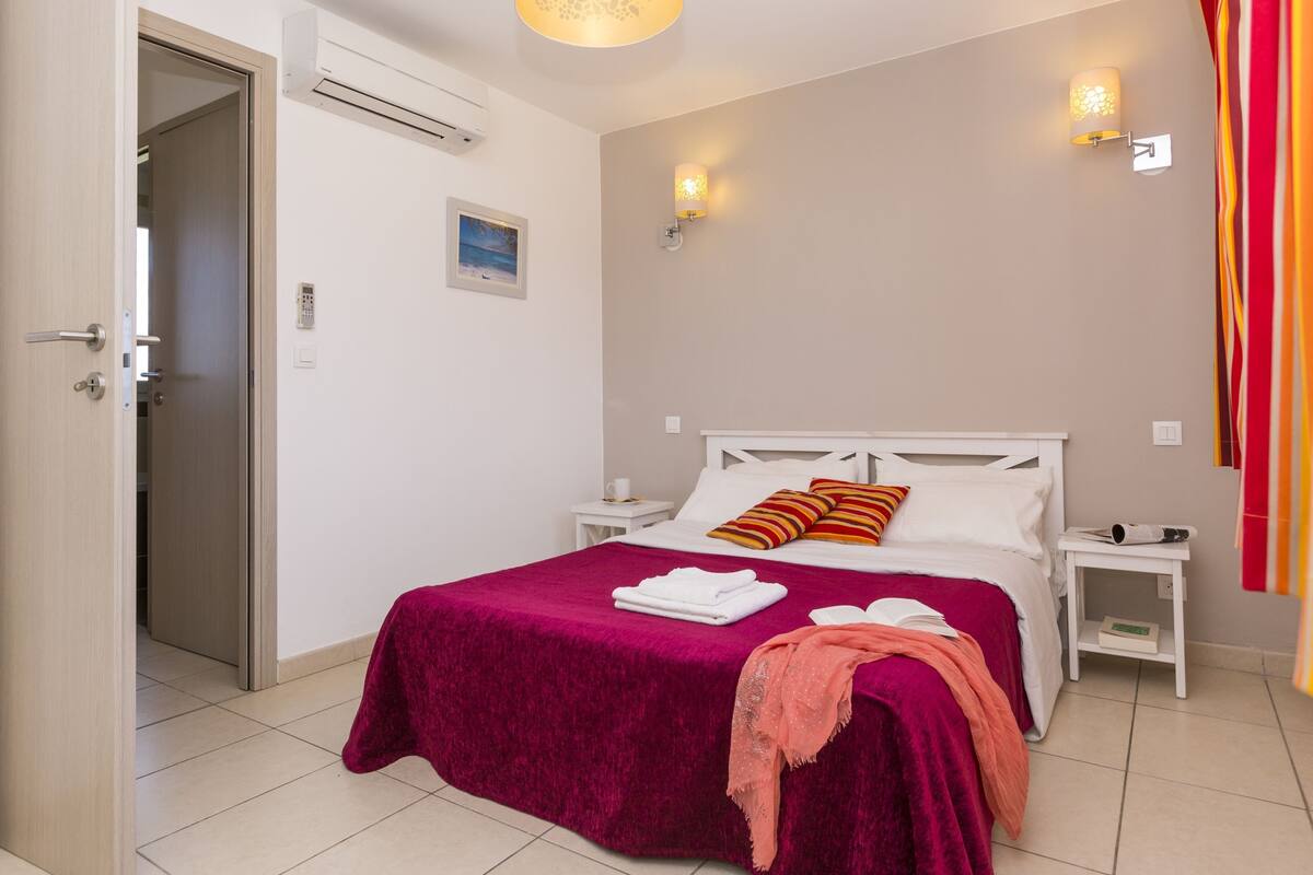 Ein Hotelzimmer mit Bett, Nachttisch, Wandlampe und Tür.