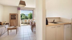 A modern kitchen with a dishwasher, a dining area with a table and chairs, and a view of greenery outside. - Résidence Odalys Les Soleils du Luberon (Bonnieux)