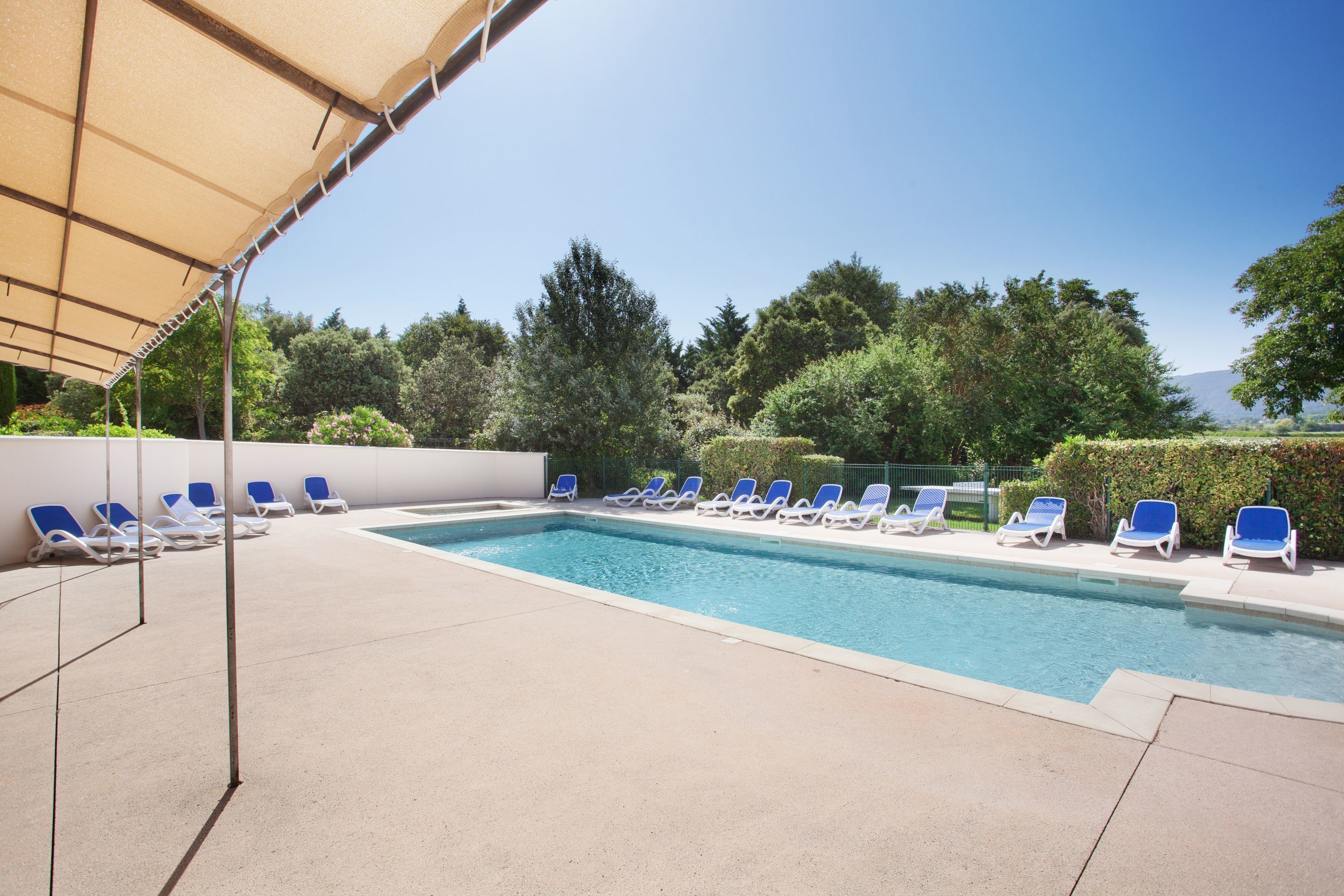 A swimming pool with blue lounge chairs and a canopy.