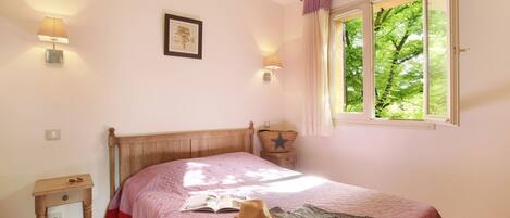 A bedroom with a bed, bedside lamps, a window with curtains, a nightstand, and a wall-mounted starfish decoration.