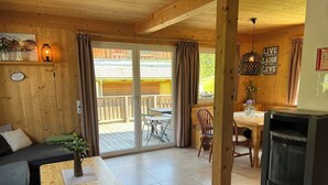 Un intérieur de chalet chaleureux avec un canapé, une table à manger et une cheminée.