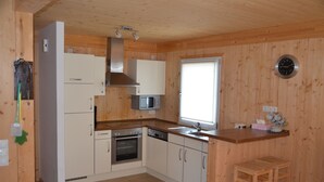 Une cuisine avec des murs en bois, des armoires blanches, un four en acier inoxydable, un four à micro-ondes et un évier.