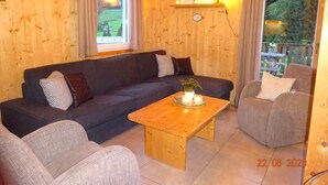 Une pièce chaleureuse avec un canapé bleu foncé, une table basse en bois et un fauteuil gris.