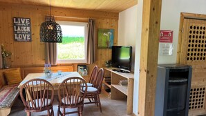 Une pièce chaleureuse avec un décor intérieur en bois, une table à manger avec des chaises, un téléviseur et une cheminée.