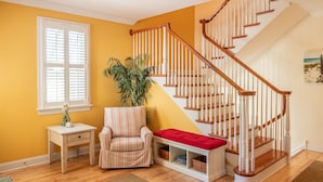 A staircase with wooden railings and a red cushioned bench at the bottom. - CORNER BEACH HOUSE (Cape May)