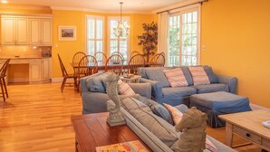 A living room with a sectional sofa, wooden coffee table, and decorative horse statues. - CORNER BEACH HOUSE (Cape May)