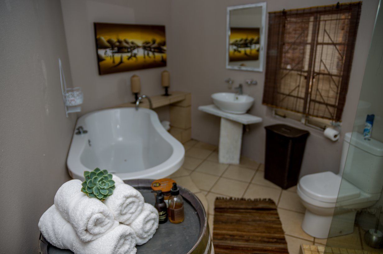 A bathroom with a bathtub, sink, toilet, and a painting on the wall.
