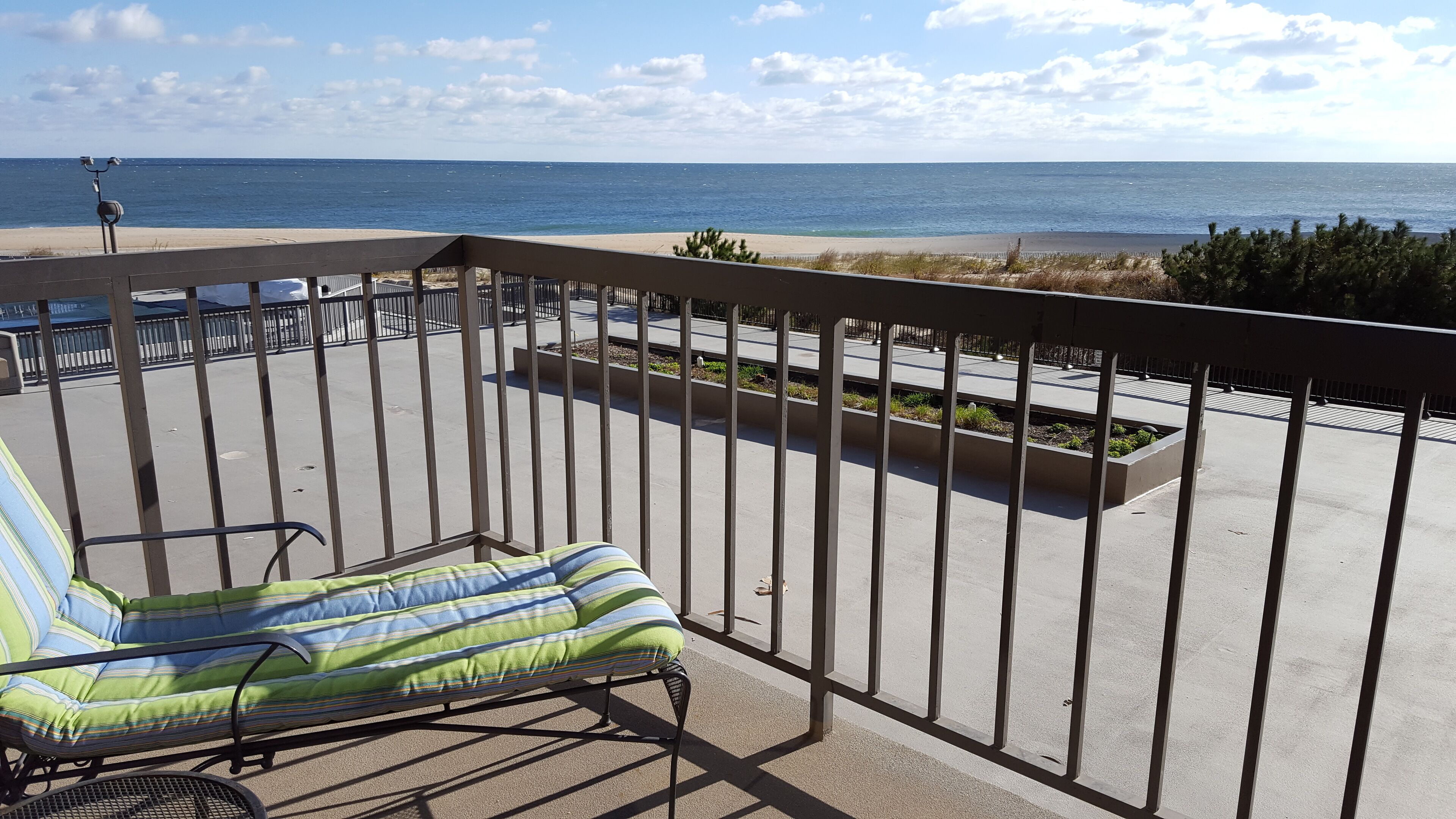 A balcony with a view of the beach and ocean.