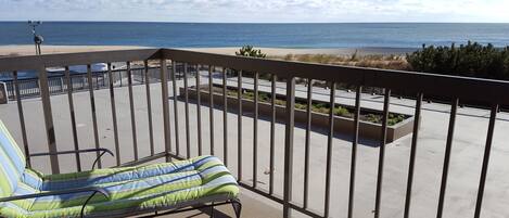 A balcony with a view of the beach and ocean.