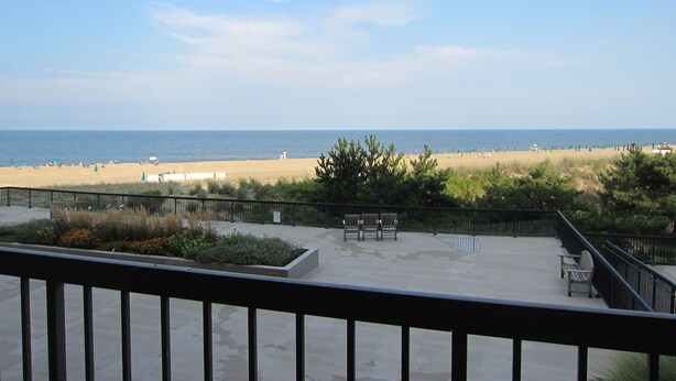 A beach view from a balcony with a railing, a sandy beach, and the ocean in the background. - Magnificent Ocean Front. Beautiful five-star. Perfect, quiet get-away. (Bethany Beach)