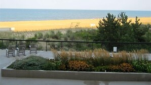 A beach view with a concrete walkway, wooden chairs, and a metal fence. - Magnificent Ocean Front. Beautiful five-star. Perfect, quiet get-away. (Bethany Beach)