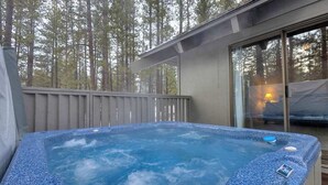 A hot tub on a deck with a view of tall trees. - Unique spacious cabin with private deck, hot tub! (Sunriver)
