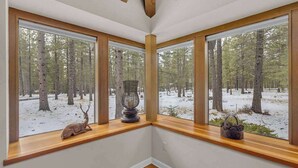 A corner room with large windows offering a view of a snowy forest. - Unique spacious cabin with private deck, hot tub! (Sunriver)