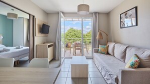 Ein modernes Hotelzimmer mit Bett, Schreibtisch, einer Sitzecke und einem Balkon mit Tisch und Stühlen.