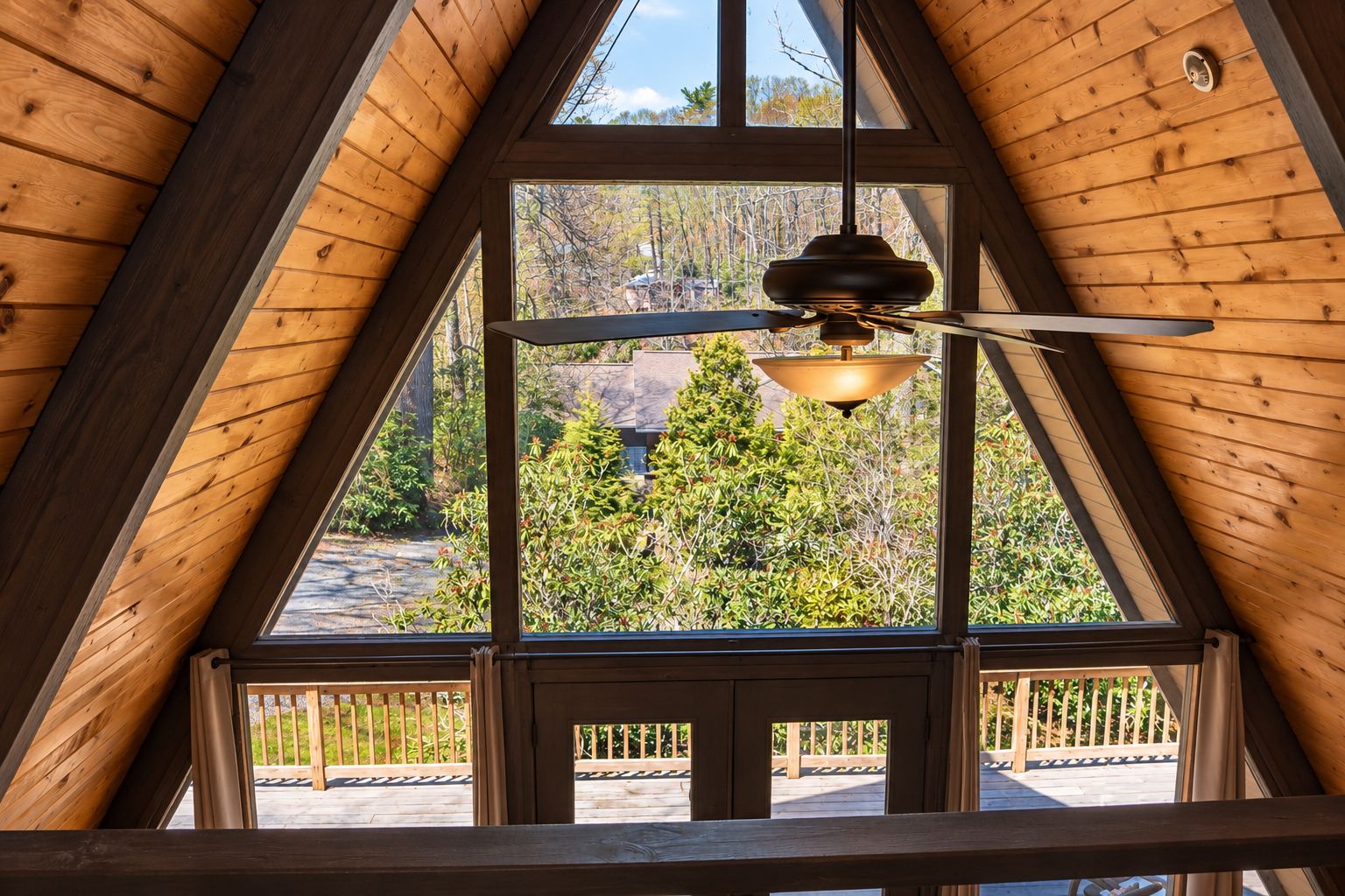 A room with a sloped ceiling, large windows, and a ceiling fan.