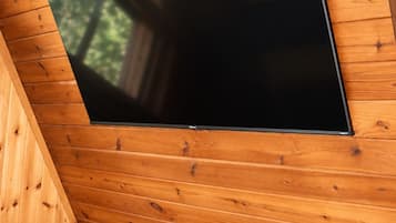 Un interior de madera con un televisor de pantalla plana montado, un sillón de cuero y una cesta de mimbre.