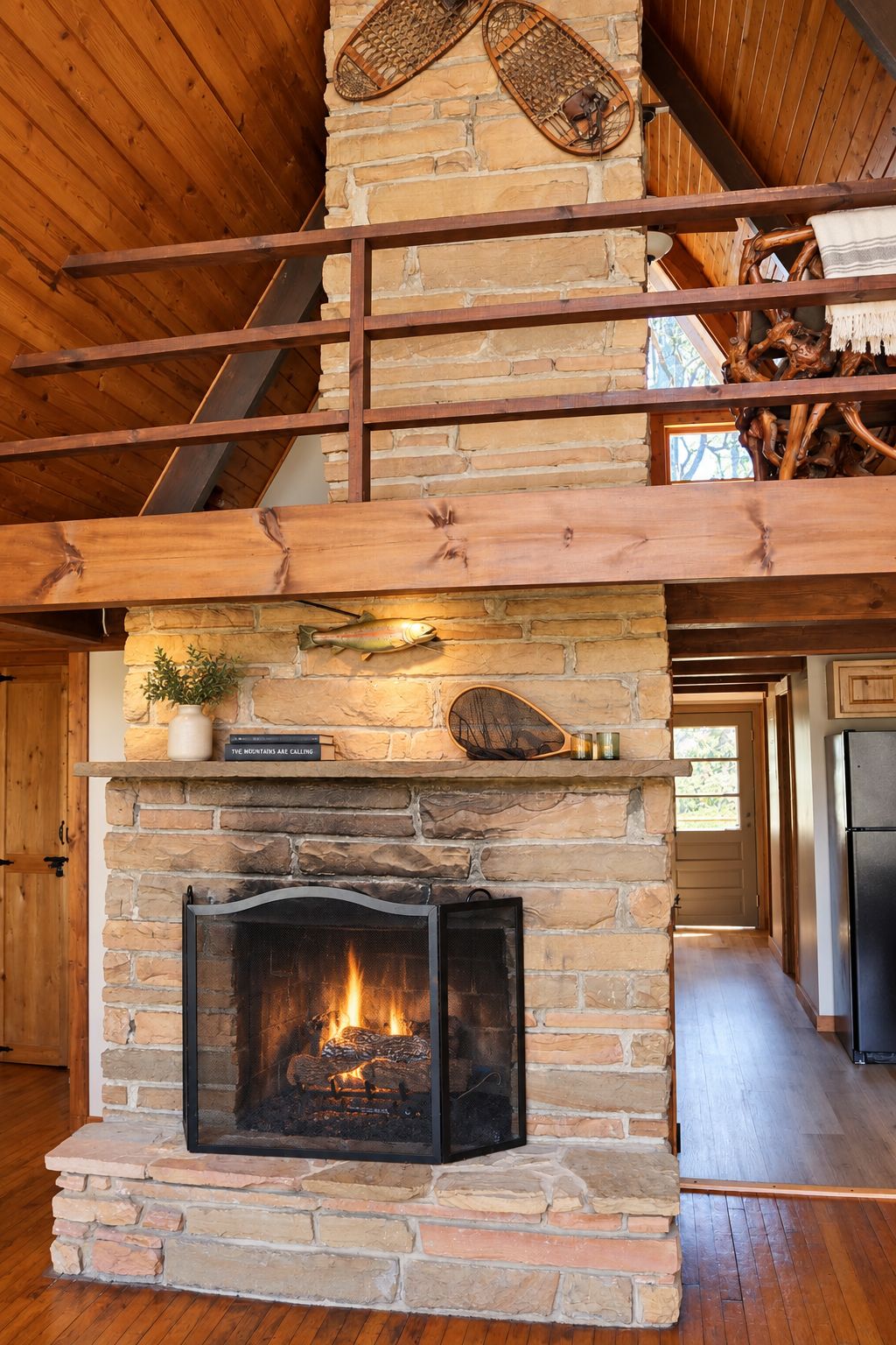 A stone fireplace with a fire, wooden beams, and a rustic interior.