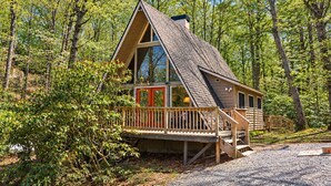 Une cabane dotée d’un toit à forte pente, de grandes fenêtres et d’une terrasse en bois.