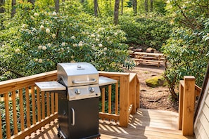 En Char-Broil-grill på ett trädäck med utsikt över en trädgård.
